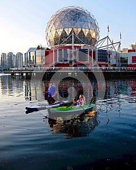 Active married couple boating and kayaking in city harbor False Creek near Yaletown.