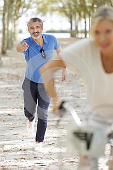 active mature couple riding bike in park