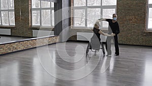 Active mature dancers in masks dancing in ballroom