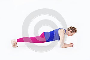 Active mature female instructor in elbows-plank position during Pilates/Yoga class