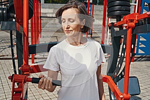 Active mature lady training with sport machine outdoors