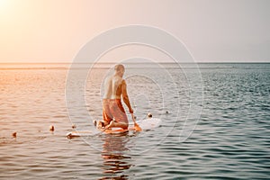 Active mature male paddler with his paddleboard and paddle on a sea at summer. Happy senior man stands with a SUP board