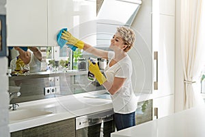 Active merry woman cleaning kitchen