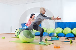 Active middle-aged woman working out with stability ball taking part in group fitness class