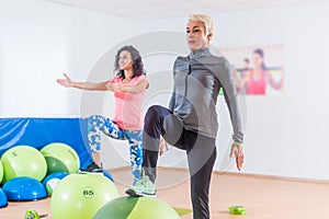 Active middle-aged woman working out with stability ball taking part in group fitness class