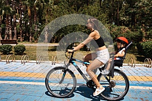 Active mother and child riding a bike together on outdoors background. Caucasian woman and baby boy on a bicycle