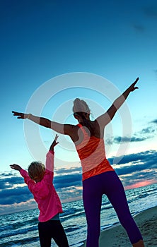 Active mother and child on seashore on sunset rejoicing