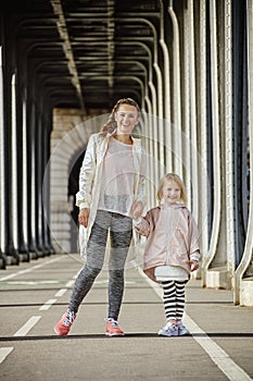 Active mother and daughter standing on Pont de Bir-Hakeim bridge