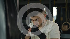 Active motivated sportsman male professional fighter boxer training boxing with punching bag in gym tired man Caucasian