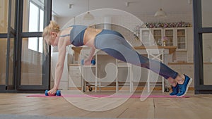 Active motivated sporty fit senior woman practicing renegade plank row