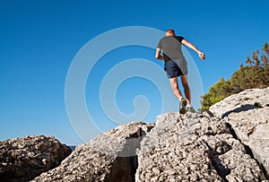 Active mountain skyrunner dressed black t-shirt and running shoes jogging the cliff summit during the morning scamper. Sporty