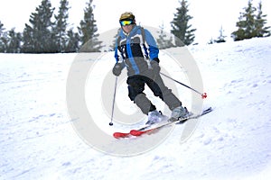 Active old aged senior experienced mature skier man in ski helmet, goggles, suit riding skies mountain peak, slope