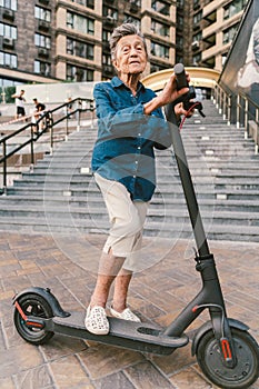 Active old woman riding electric scooter. Retired lady uses environmentally friendly city vehicle. Granny very old with