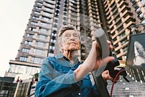 Active old woman riding electric scooter. Retired lady uses environmentally friendly city vehicle. Granny very old with