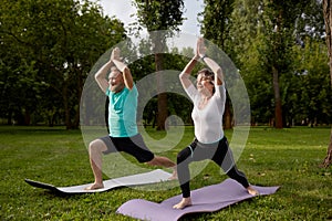 Active older couple doing yoga exercise outdoors at city park