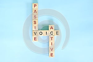 Active and Passive voice topic in English grammar teaching. Wooden block crossword puzzle flat lay in blue background.