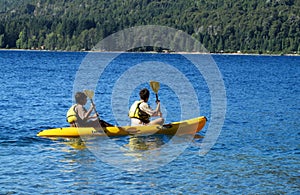 Active people in kayaks wearing lifejackets with paddles