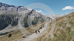 Active people walking up on the mountain trail. Clip. Group of hikers exploring breathtaking summer trail on rocks and