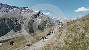 Active people walking up on the mountain trail. Clip. Group of hikers exploring breathtaking summer trail on rocks and