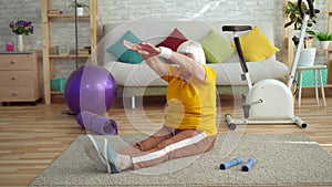 Active positive elderly woman makes a warm-up on the carpet in the living room