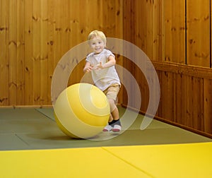 Active preschool boy playing with big ball in indoor sports hall/gym class