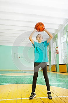Active preteen girl tossing basketball in rim