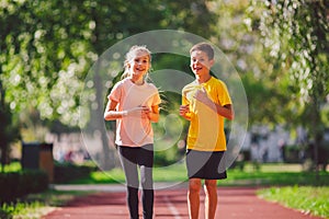Active recreation and sports children in pre-adolescence. Caucasian twins boy and girl 10 years old jogging on red rubber track