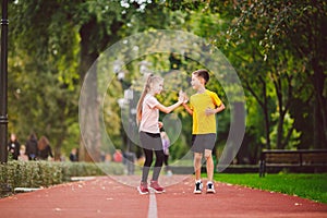 Active recreation and sports children in pre-adolescence. Caucasian twins boy and girl 10 years old jogging on red rubber track