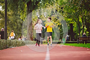 Active recreation and sports children in pre-adolescence. Caucasian twins boy and girl 10 years old jogging on red rubber track
