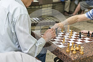 Active retired people, old friends and free time, seniors having fun and playing chess game at park. Waist up. Old men playing