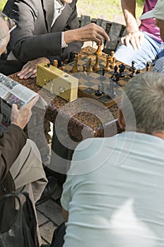 Active retired people, old friends and free time, seniors having fun and playing chess game at park. Waist up. Old men playing