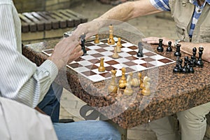 Active retired people, old friends and free time, seniors having fun and playing chess game at park. Waist up. Old men playing