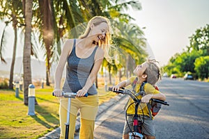 Active school kid boy and his mom riding a bike with backpack on sunny day. Happy child biking on way to school. Safe