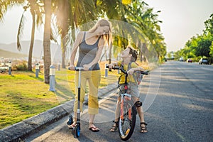 Active school kid boy and his mom riding a bike with backpack on sunny day. Happy child biking on way to school. Safe