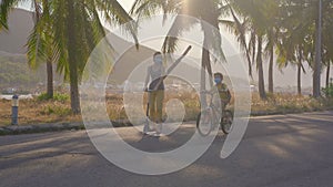 Active school kid boy and his mom riding a bike and scooter with backpack on sunny day. Happy child biking on way to