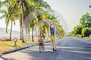 Active school kid boy and his mom in safety helmet riding a bike with backpack on sunny day. Happy child biking on way