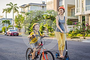 Active school kid boy and his mom in safety helmet riding a bike with backpack on sunny day. Happy child biking on way