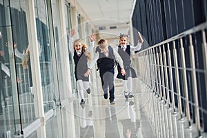 Active school kids in uniform running together in corridor. Conception of education