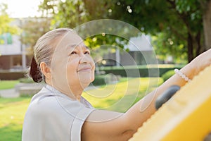 Active senior Asian woman doing hands exercise at exercise equipment in the park