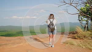 Active senior Asian woman hikes Pidurangala Rock. Mature traveler explores, enjoys serene mountain landscape. Solo hiker