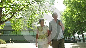 An active senior caucasian tourist couple walking in london backlit by the sun