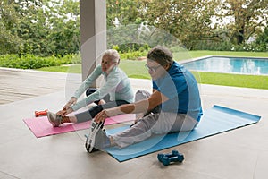 Active senior couple doing stretching exercise in the porch at home