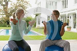 Active senior couple exercising with dumbbell in porch at home