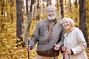 Active senior couple hiking in forest or park. Mature man and woman Happily smiling.