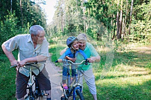 Active senior couple with little granddaughter on bikes in nature