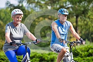 Active senior couple riding bicycle in park
