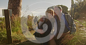 Active senior couple sitting on the floor in forest