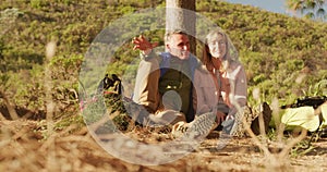Active senior couple sitting on the floor in forest