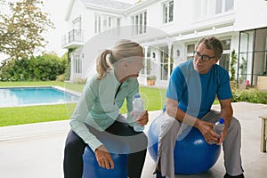 Active senior couple talking with each other after workout in the porch at home