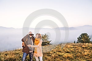 Senior couple with binoculars on a walk in an autumn nature.